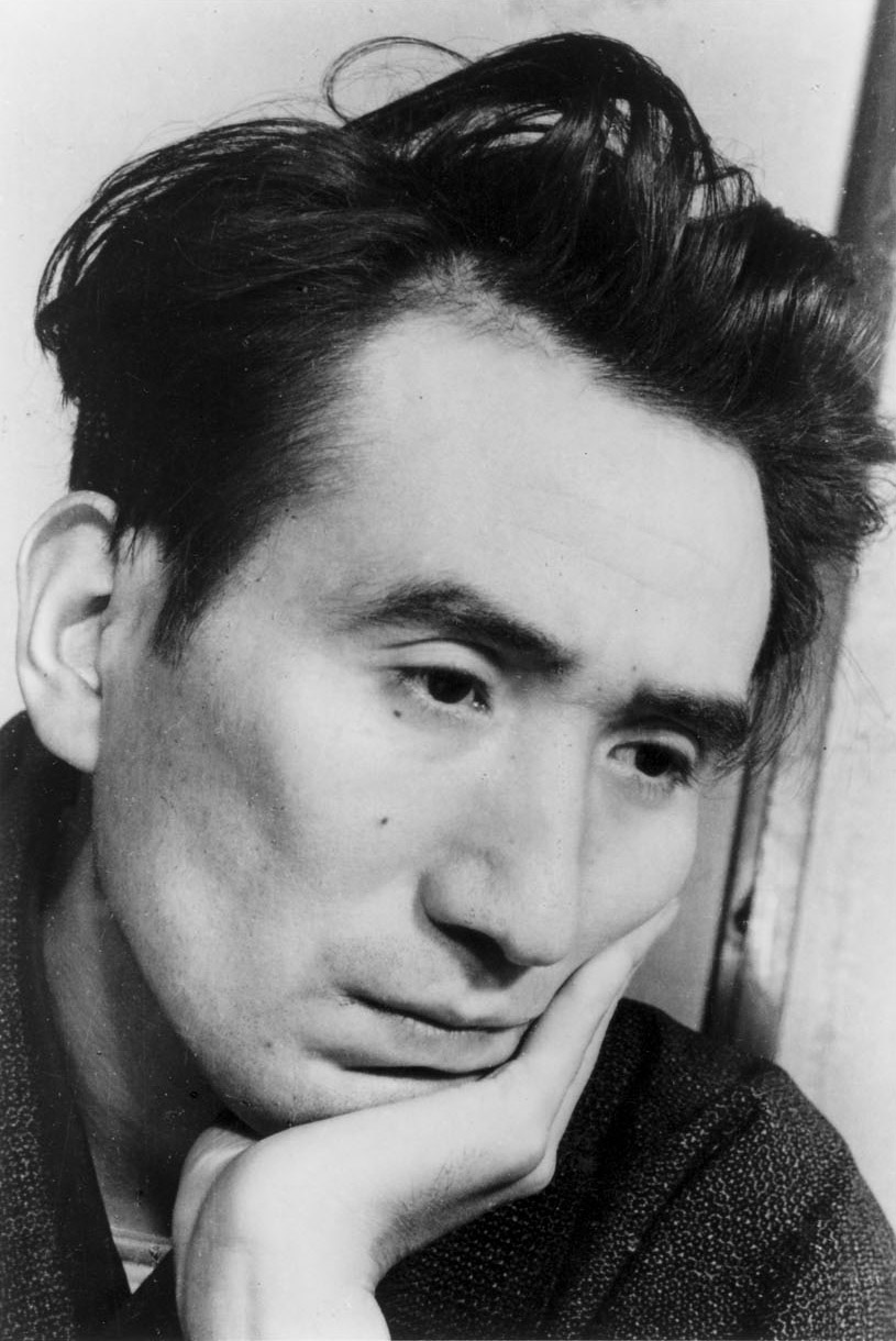 頬づえをついて、こちらを見る太宰治の肖像写真（顔の接写）。